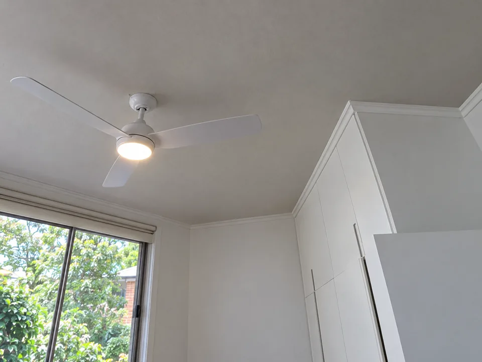White ceiling fan with light in a white room with built-in cabinets and window in Normanhurst